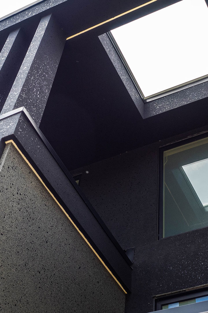 Custom stucco work above main entryway featuring large mica flakes embedded in black and grey stucco