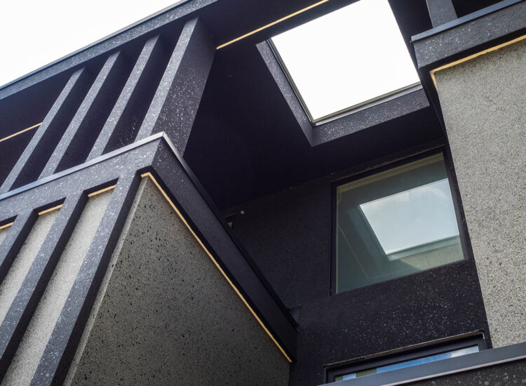 Custom stucco work above main entryway featuring large mica flakes embedded in black and grey stucco