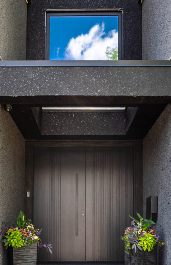Custom entryway with large double doors, stucco archway, and skylight.