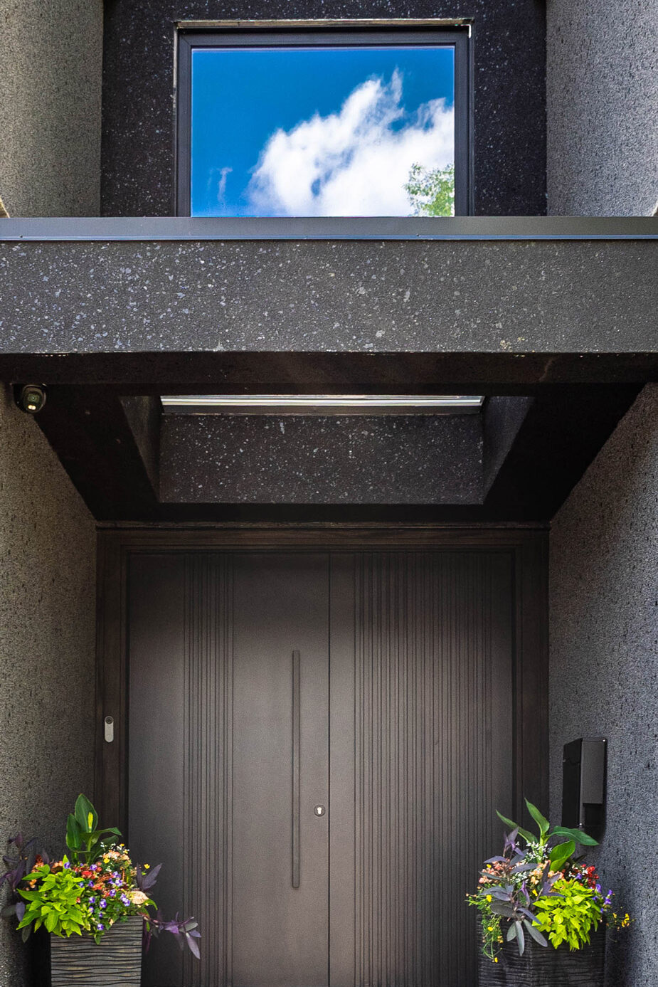 Custom entryway with large double doors, stucco archway, and skylight.
