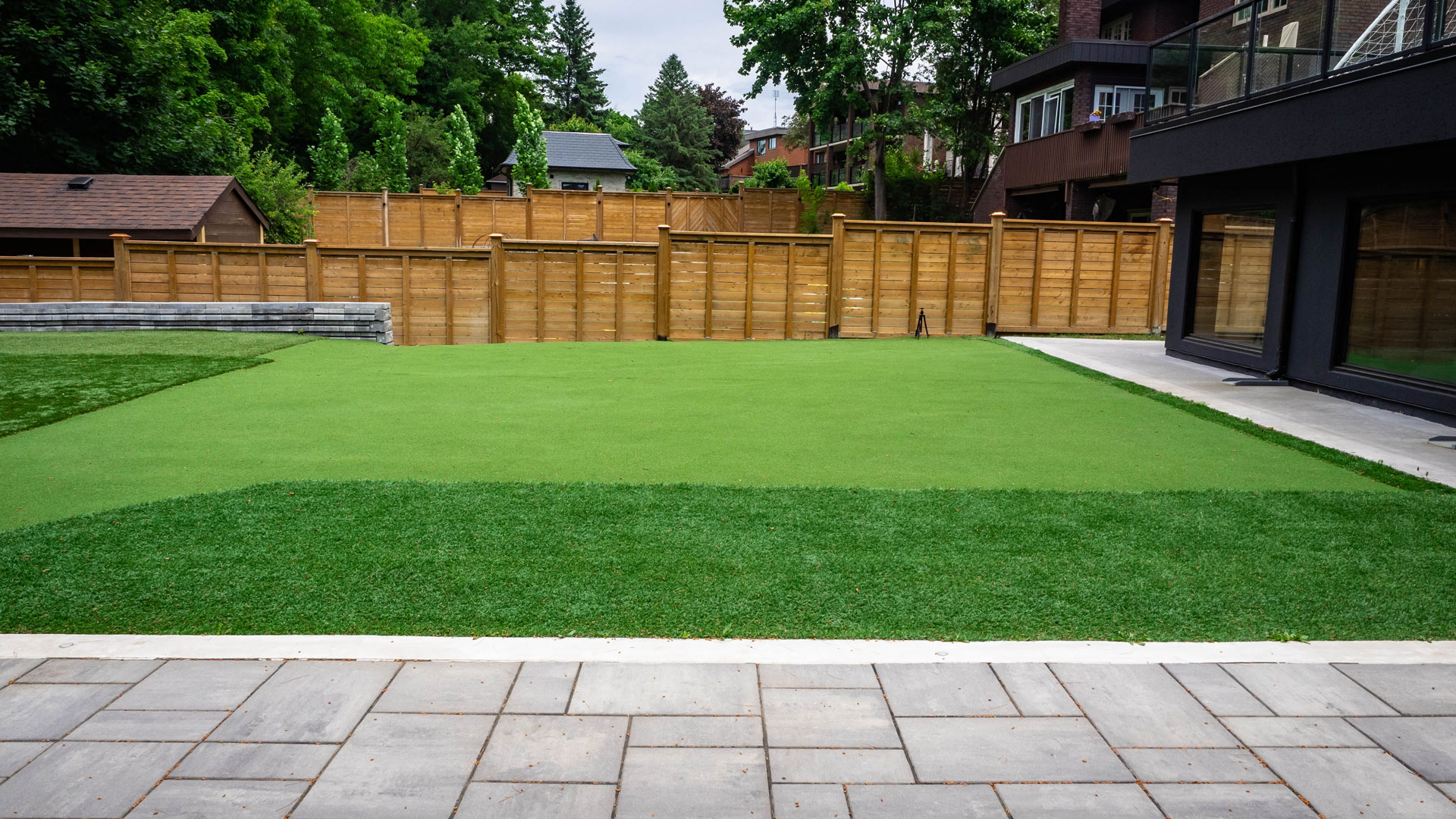 Custom landscaping in backyard featuring an artificial grass soccer field